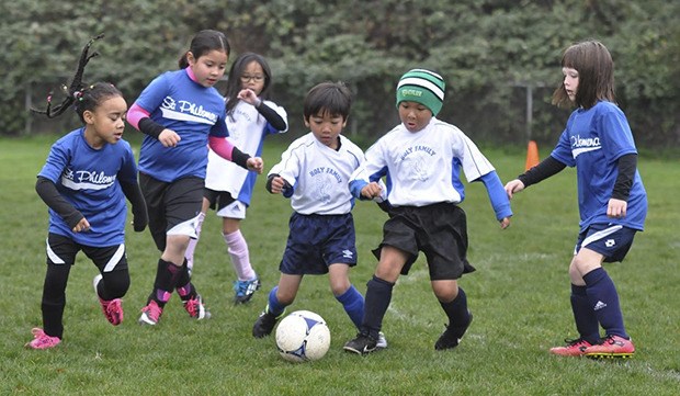 Holy Family School’s first-grade soccer team battles St. Philomena of Des Moines for the ball in a recent match on the home pitch. The school participates in the Catholic Youth Organization Athletics.