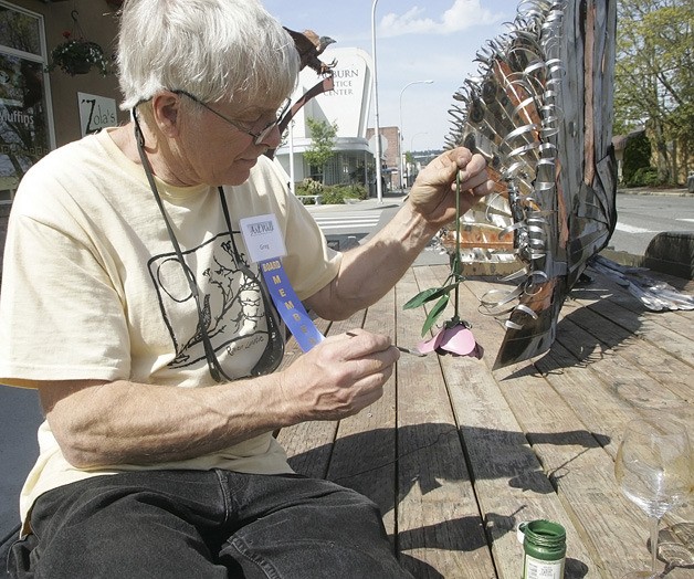 Greg Bartol paints a metal rose for his display of a 6-foot wide metal peacock during last year's inaugural Art Walk.