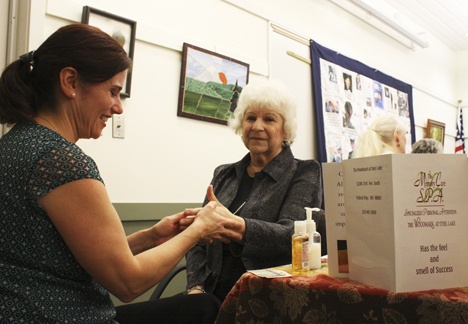 Auburn resident Lorraine Stone gets a free hand massage from Stacey Deese