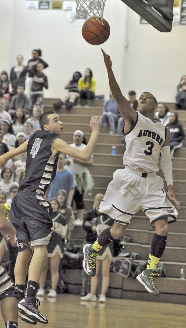 Auburn's Harold Lee drives around Auburn Riverside's Devon Larson to deliver a shot during the Trojans' 67-34 win over the Ravens on Friday. Lee had 13 points in the win.