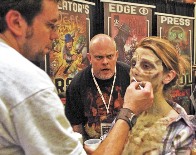 Chuck Messinger reacts with horror as a zombie receives her makeup at the Bandersnatch Studios booth at ZomBcon. Messinger