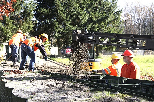 King County workers fill new HESCO barriers at Pacific City Park.