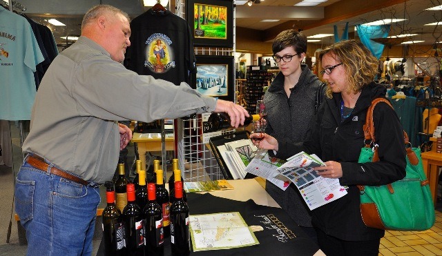 Richard Corella from Chandler Reach Vineyards pours Sierra Henderson and Natalie Laszewski some wine during Friday's Art Walk and Wine Tasting event.