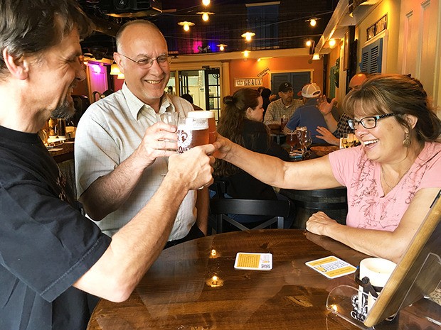 Smiling beer connoisseurs hoist a couple of cool ones at Bellevue’s Geaux Brewery