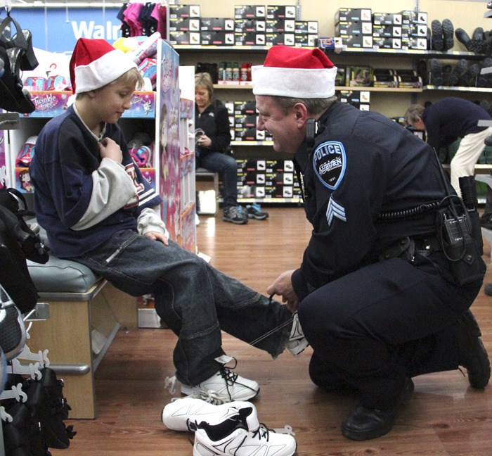 Sergeant Brian Williams laces up a new pair of sneakers for Kyle Joyce during the Auburn Police Officer's Association's Shop With a Cop.