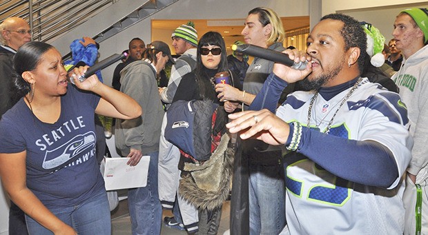 Latonya Chaffer and Eric Kieth from 1ONE sings to the crowd while fans wait to get autographs from visiting Seahawks at Auburn Volkswagen on Tuesday night. Seahawks cornerback Byron Maxwell and linebacker Bruce Irvin joined former Seahawk Lawyer Milloy in signing autographs for fans. The players’ appearances was part of a canned food and toy drive at the dealership.