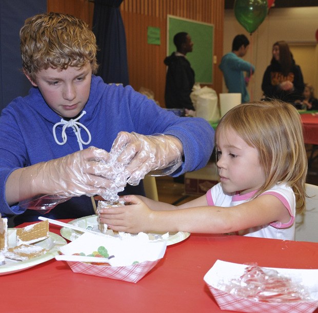 Sam Elkins helps Maddie Lane make a graham cracker house during last weekend's Snack and Craft at Washington Elementary School.