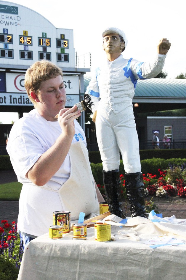 Alex Harwood paints the West Point Thoroughbreds silk colors on the jockey in the winner's circle at Emerald Downs during Mile festivities last Sunday. California invader Awesome Gem captured the 76th running of the Grade III Longacres Mile.