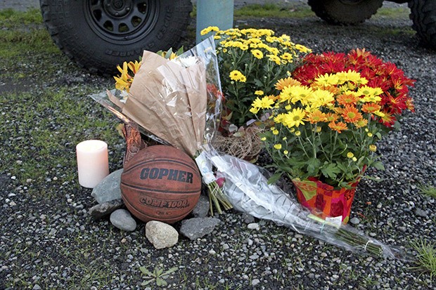 Family and friends contribute to a memorial on the East Valley Highway in front of The Log Cabin Pub in Sumner