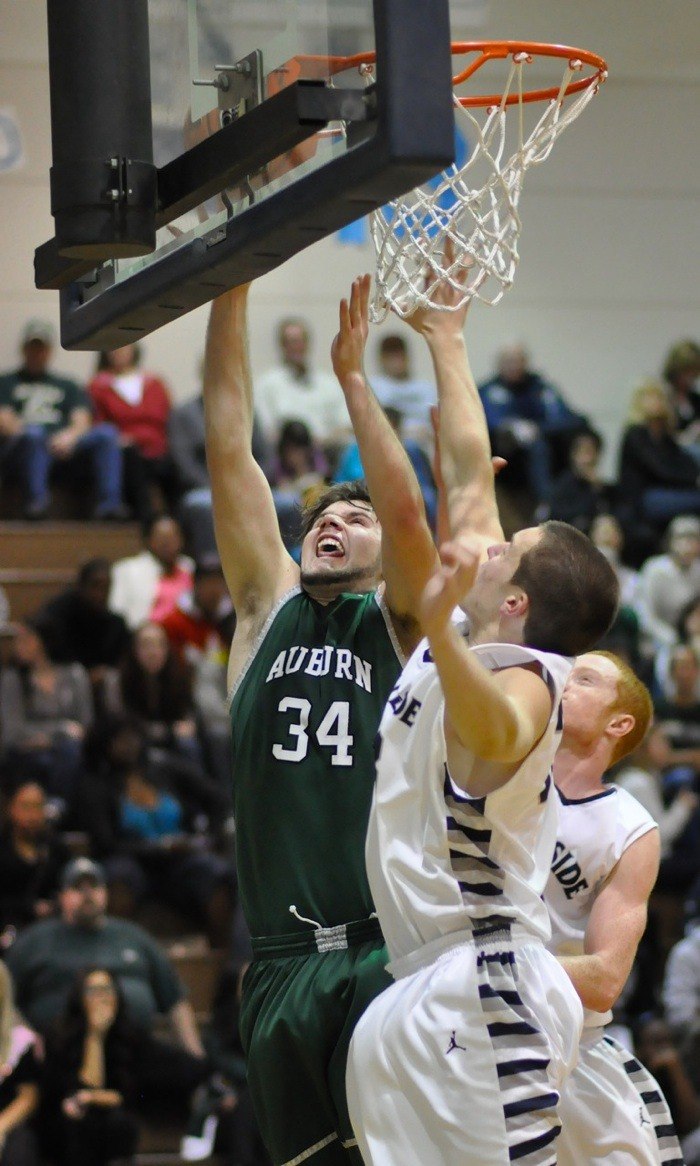 Auburn senior Spencer Fisher fends off a pair of Ravens for a rebound.