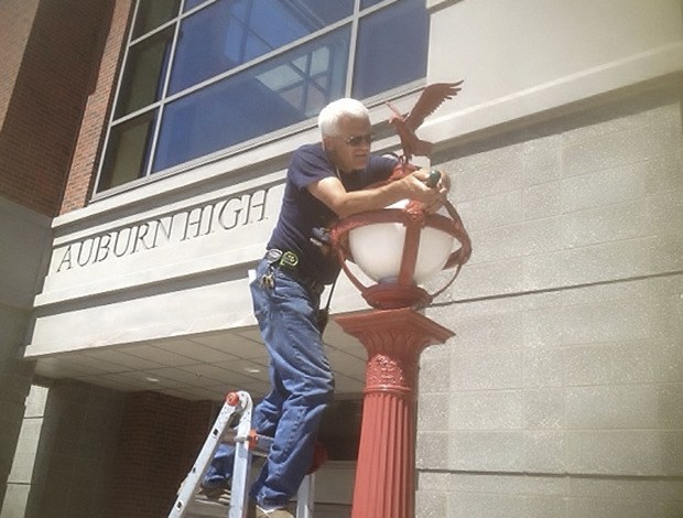 Auburn School District staff member Tim Campbell installs the newly refurbished lampposts at Auburn High School.