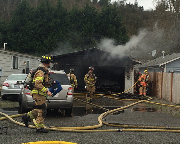 VRFA firefighters mop up after dousing a fire that destroyed an Algona garage Sunday. The residents were not at home when the fire occurred.