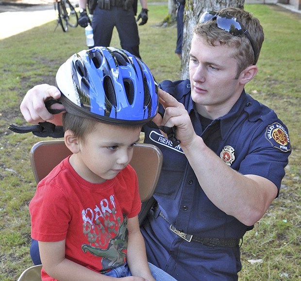 VRFA Firefighter Steve Rierson fits a bike helmet on Damon Garcia