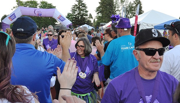 Cancer survivors exchange high-fives after completing a ceremonial lap around Auburn Memorial Field during the Relay for Life event Friday.