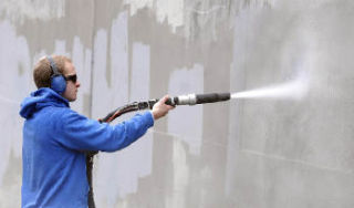 Brent Christopherson from Surface Cleaning Technologies removes graffiti from a concrete wall on 5th Street Southeast as part of a demonstration.