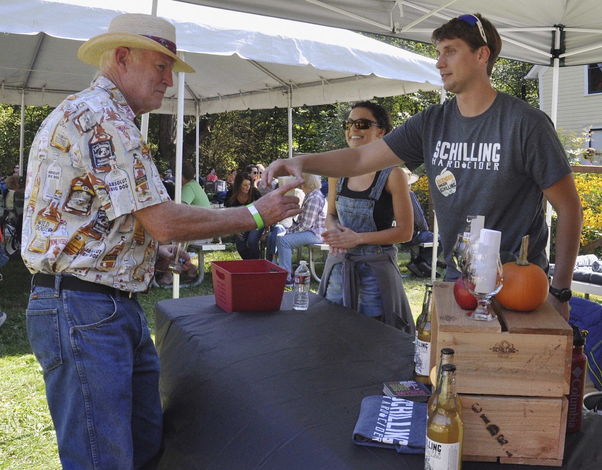 Phil Eversole takes a beer from Matt Acker and Nicole Ledford of Schilling Hard Cider during the seventh annual Hops & Crops Festival at Mary Olson Farm last Saturday. RACHEL CIAMPI