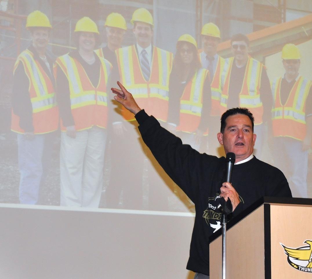 Principal Eric Daniel points out the building of Arthur Jacobsen Elementary School in photos of yesteryear in the AJ gym during a 10-year celebration of the school Thursday. Daniel has been the school's only principal. RACHEL CIAMPI