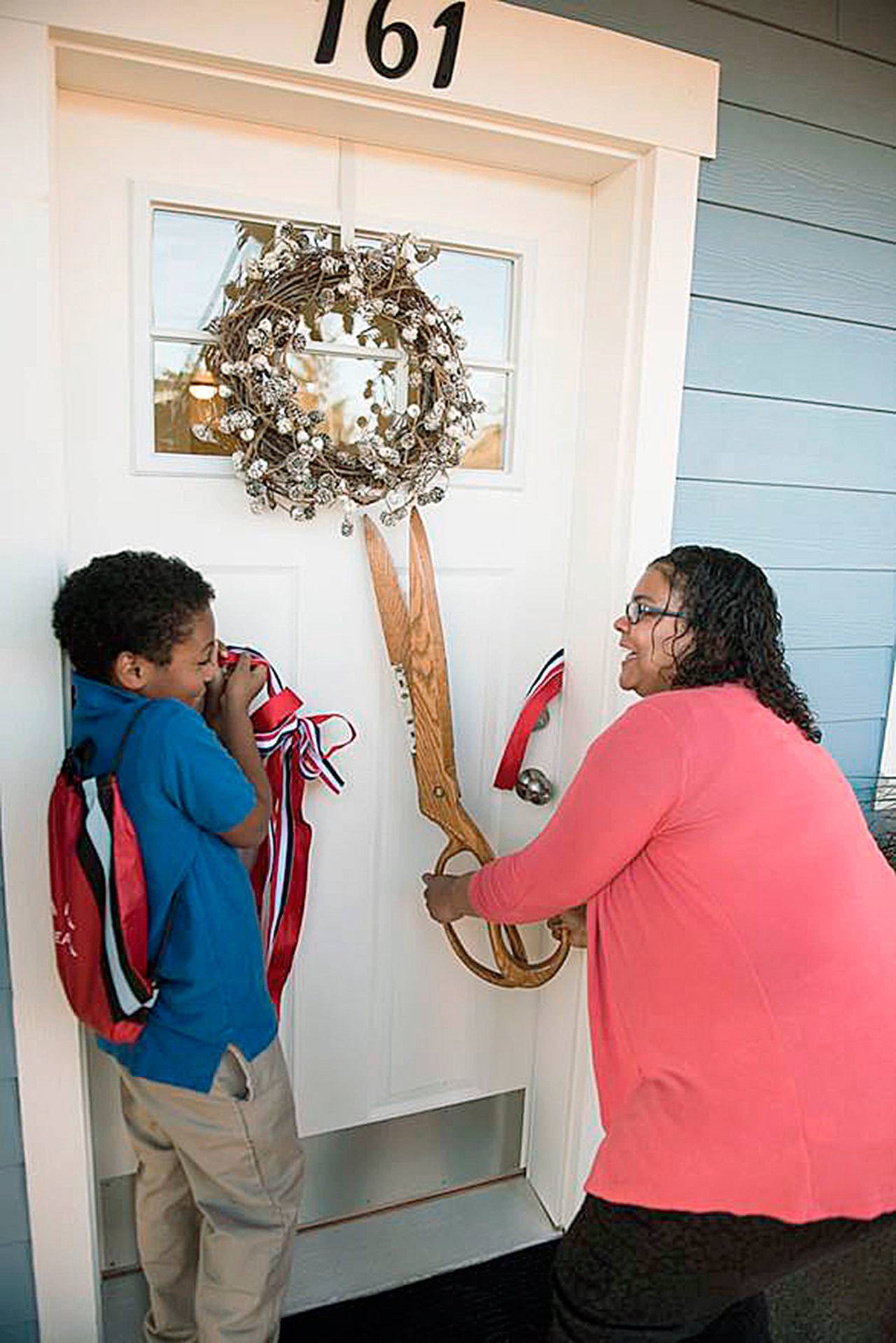 Rachel Grinage, a decorated U.S. Navy veteran, and a single mother, cuts the ribbon to her new home in Pacific with her 9-year-old son, Ahmad, during a dedication ceremony last Friday. COURTESY PHOTO