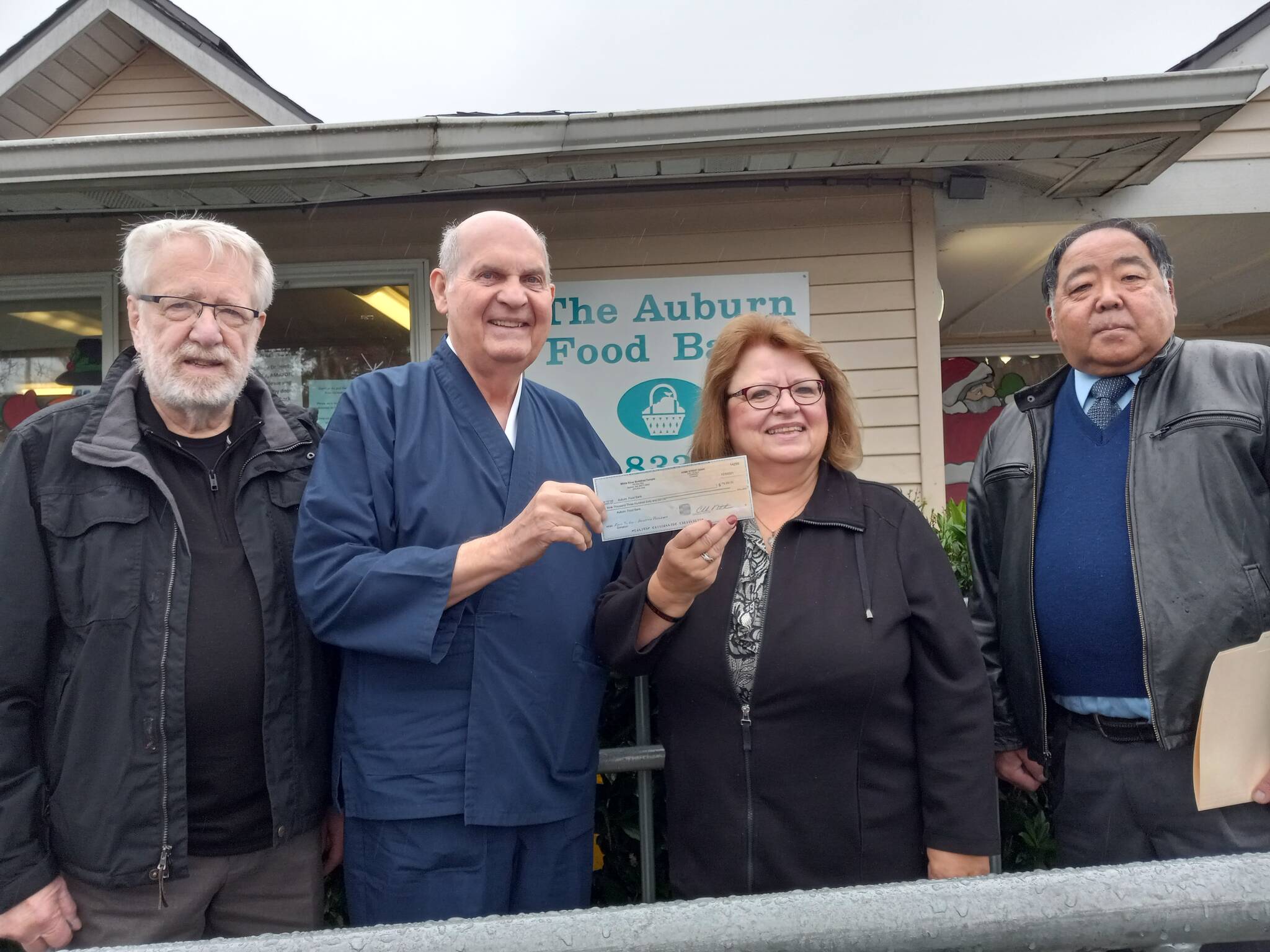 From left: White River Buddhist Temple Sensei Jim Warrick presents a $9,360 check, the proceeds of the musical revue fundraiser, to Auburn Food Bank Director Debbie Christian. At the left is temple member Don Gardner, and at the right is fellow temple member Randy Okimoto.  Photo by Robert Whale, Auburn Reporter.