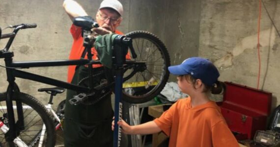 Volunteer Greg Neiman and a young helper work on a bike donated to Bikes for Kids. Courtesy photo