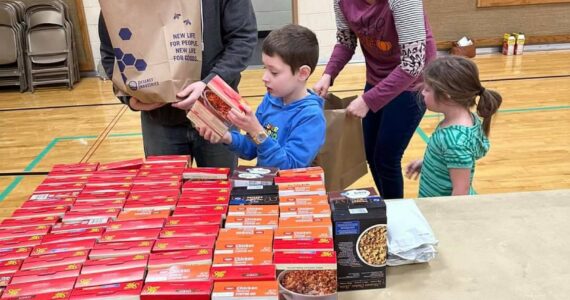 Seth and Katie Price, along with their children Isaac and Brielle, assemble meals-in-a-bag at the Auburn congregation of The Church of Jesus Christ of Latter-day Saints for families in need, as part of a food drive benefiting Vine Maple Place. Courtesy photo.